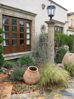 Antique olive jar sits in a bed garden stones with elfin thyme and Spanish lavender in Los Angeles